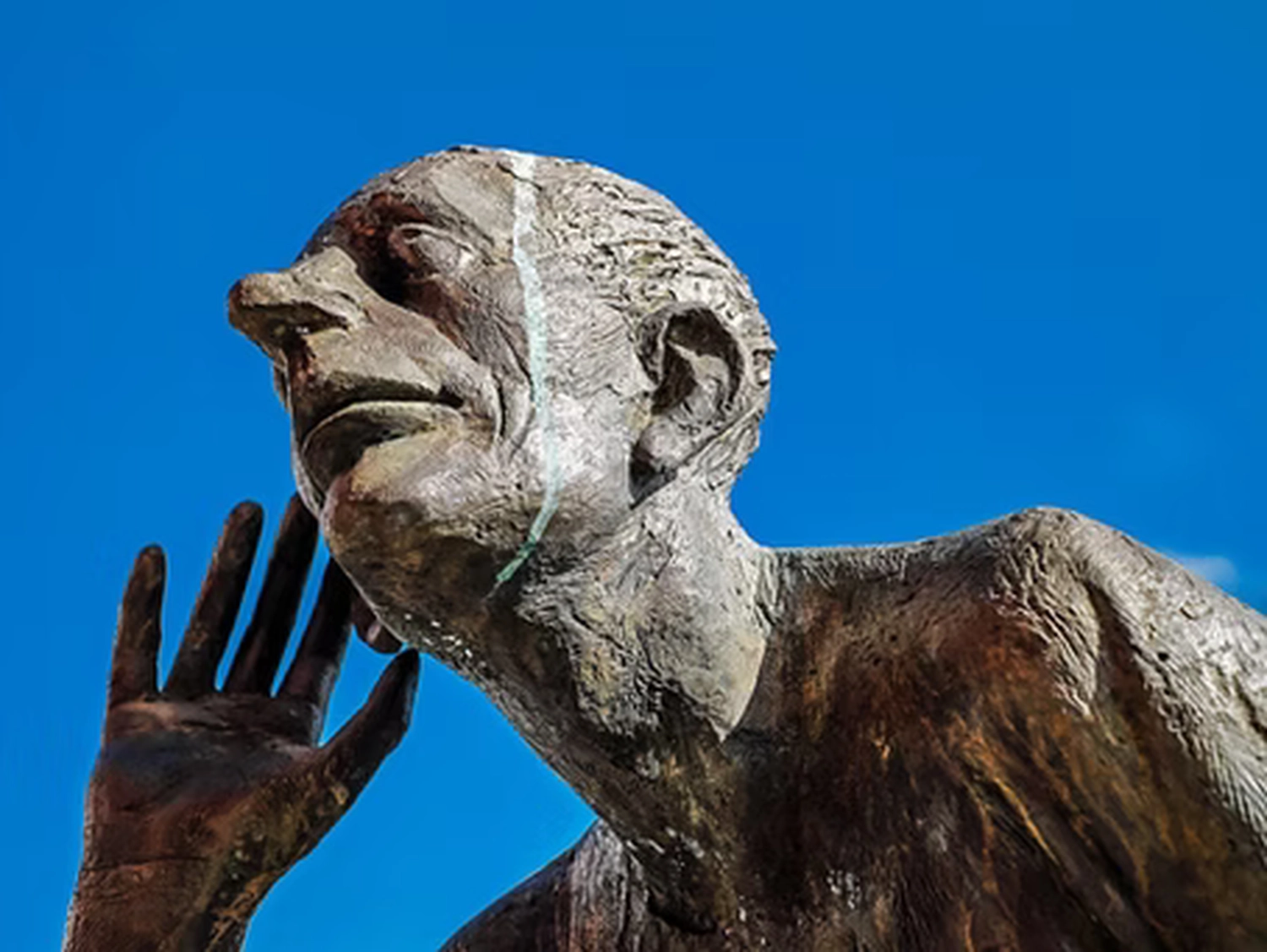 Wirtschaftsverein Apollon - Projektleitung von Konvaleszenz -  Eine Nahaufnahme einer Bronzeskulptur eines Mannes, der sich nach vorne beugt und seine rechte Hand hinter sein Ohr legt, um aufmerksam zuzuhören.